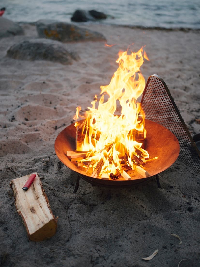 A Cricket lighter beside a blazing fireplace on a beach