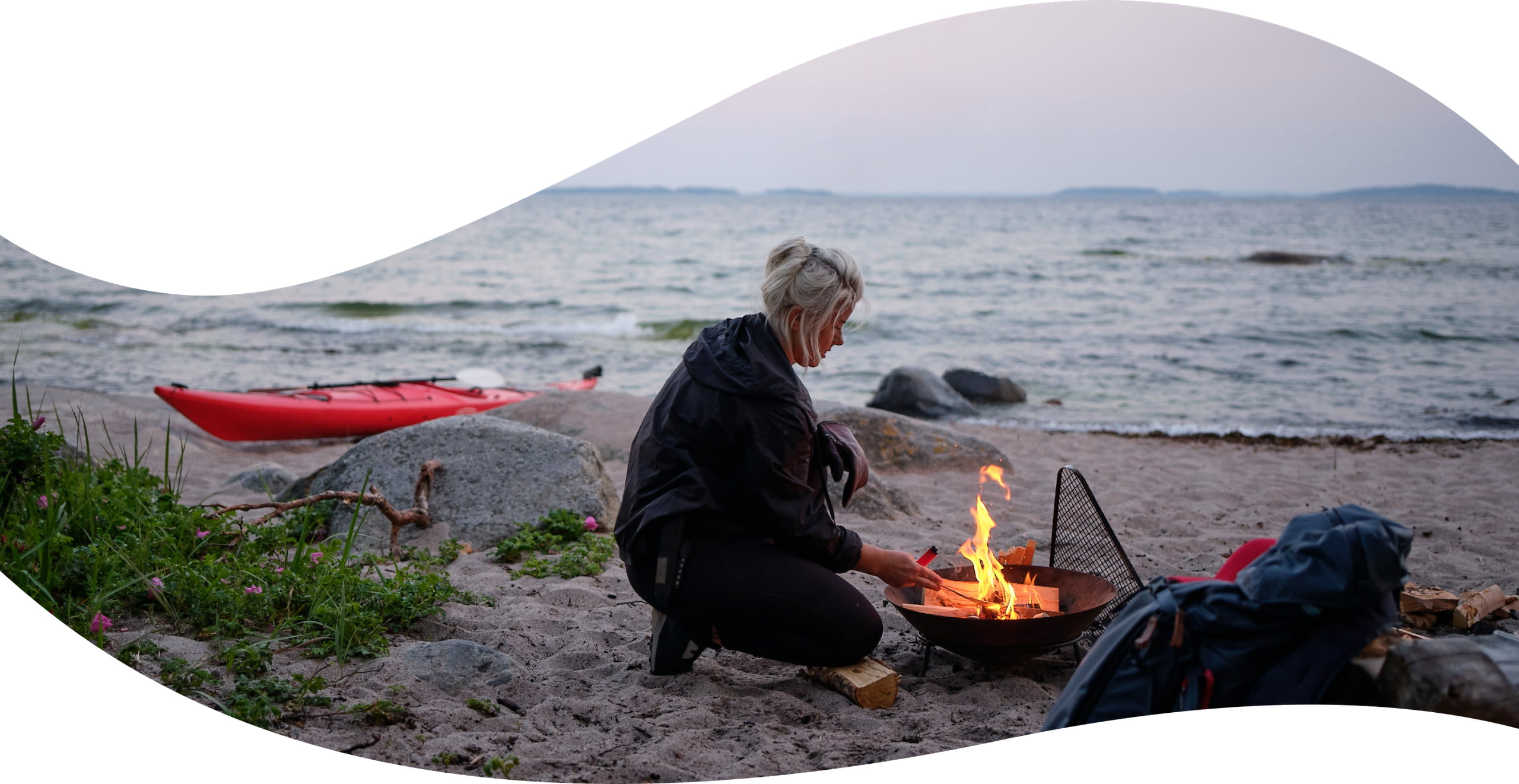 Elle lighting a fire on a beach