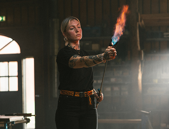 A blond woman lighting a fire