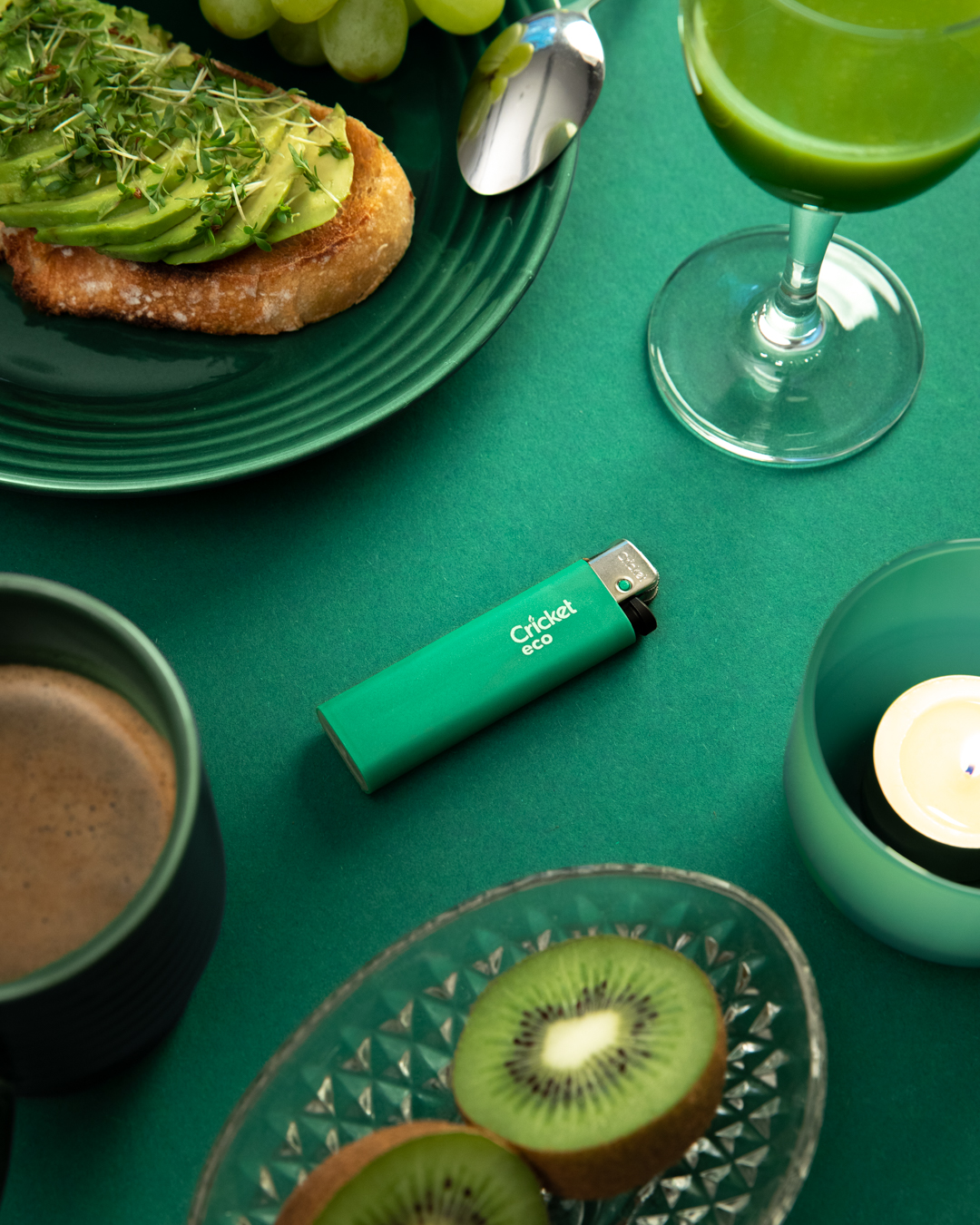 A green Cricket Eco lighter placed on a green table 